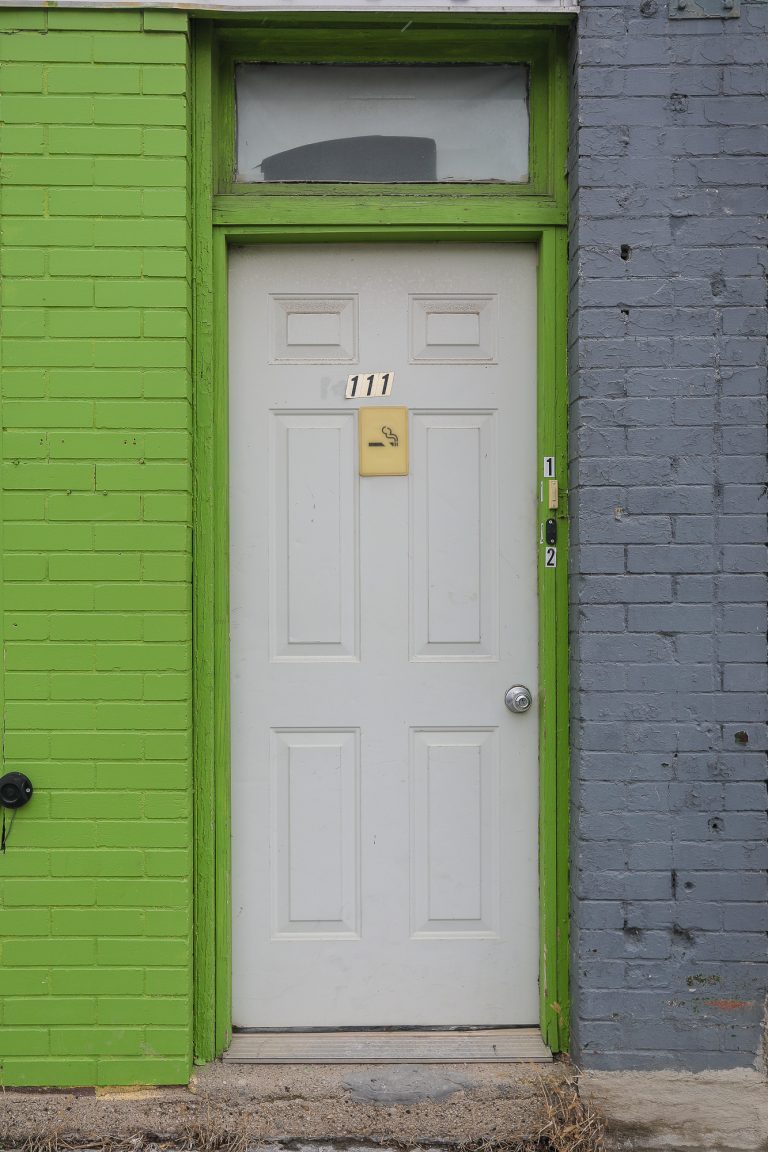 White door in a bright green building.