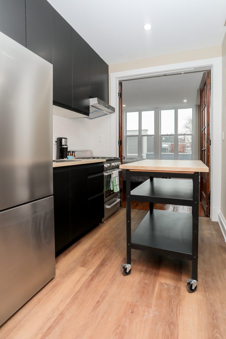 Modern kitchen with a black rolling portable kitchen island and natural wood french doors.