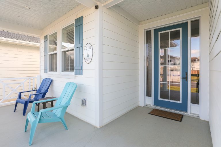 Front porch of home with white siding and blue accents.