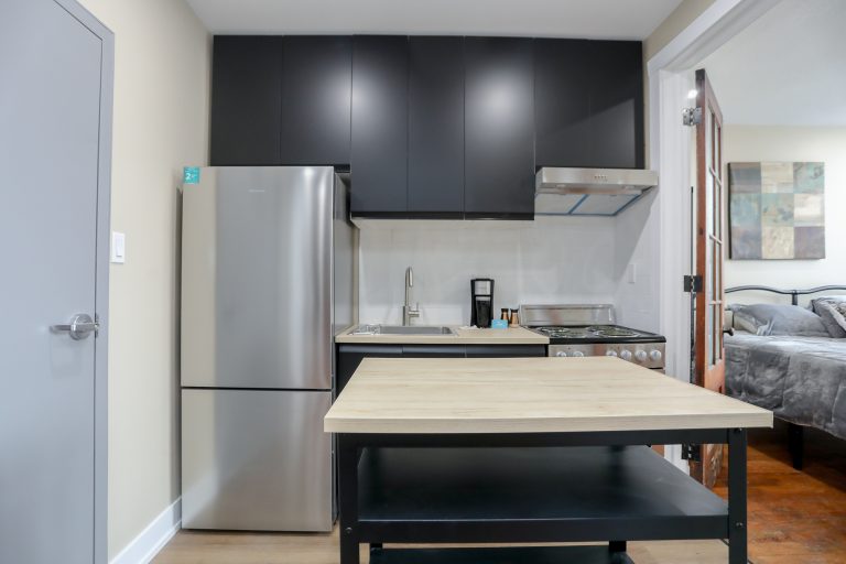 Modern kitchen with black cabinets and stainless steel appliances.