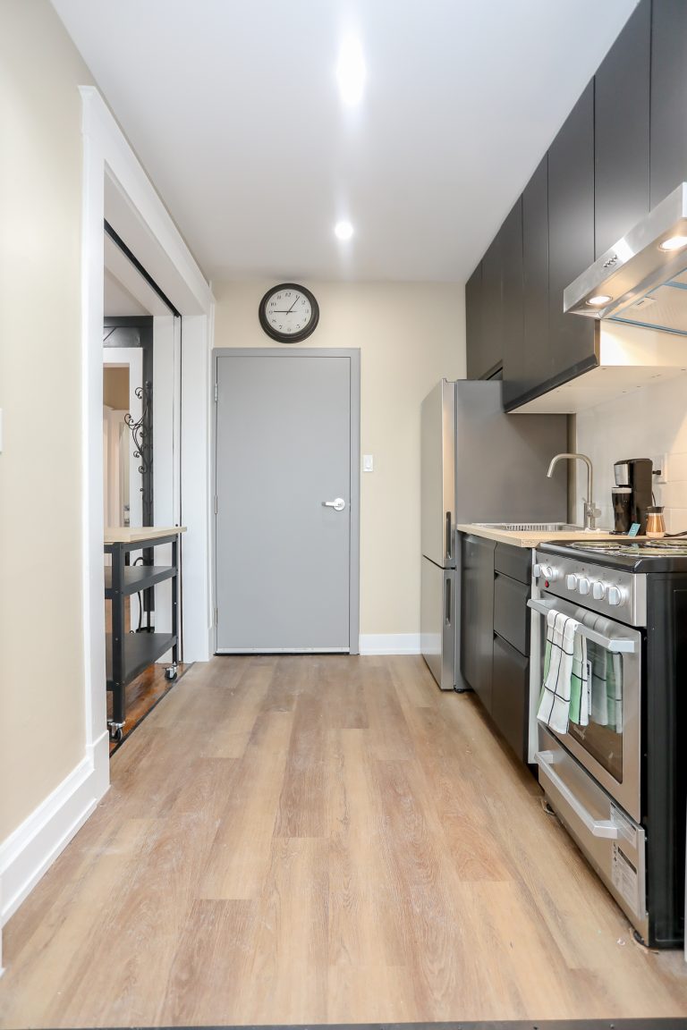 Long galley style kitchen with natural engineered hardwood.