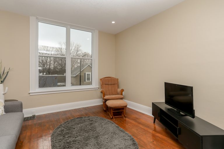 Beige living room with a brown rocking chair in the corner.