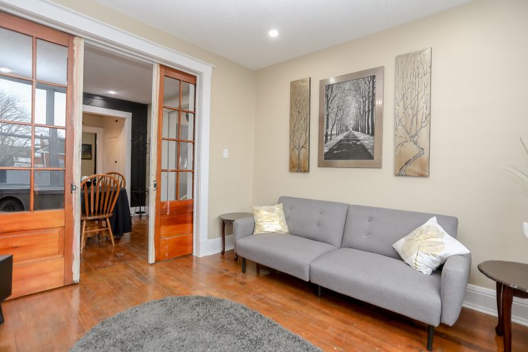 Cozy living room with natural wood floors and a grey love seat.