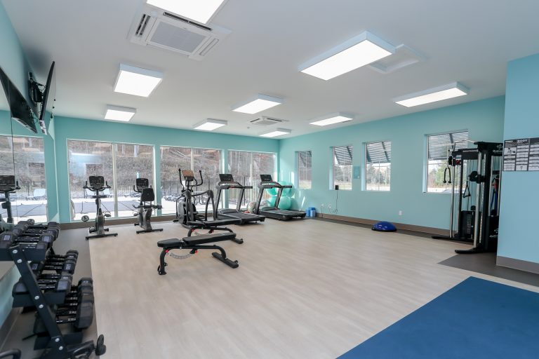 Teal exercise room with cardio and weight equipment.