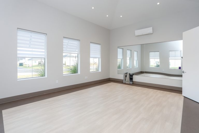Clean white yoga studio with light hardwood floors.
