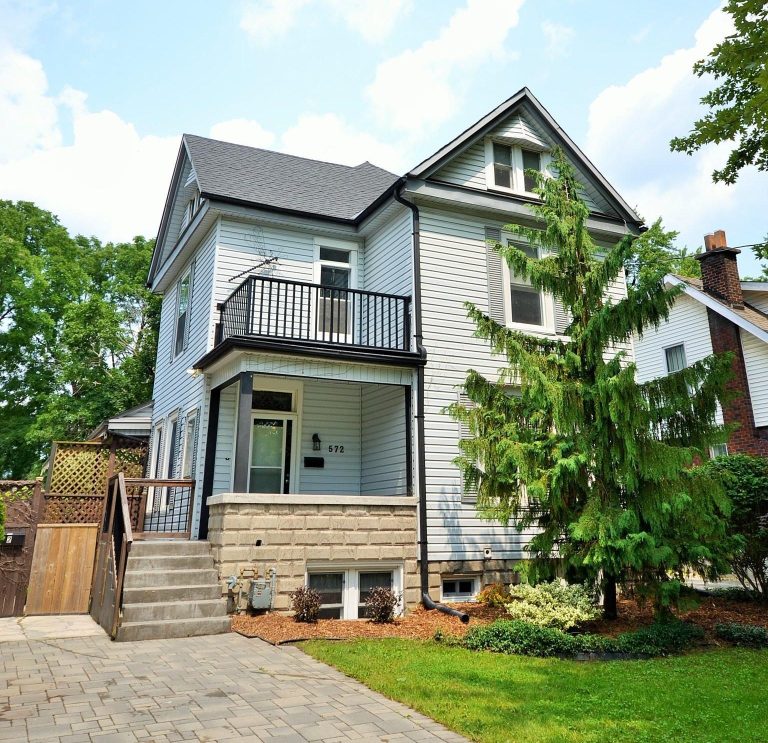 Two story home with white siding and black railing on upper patio.