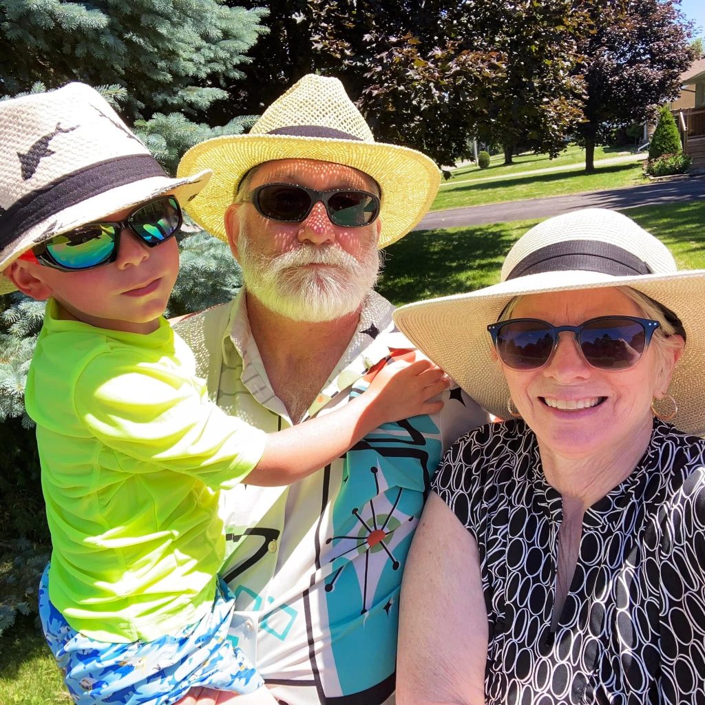 Smiling grandparents holding their young grandson.